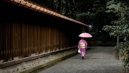 geisha holding umbrella near fence